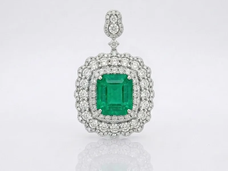 The same emerald and diamond pendant generated on a plain pale background with a soft mirrored reflection beneath it