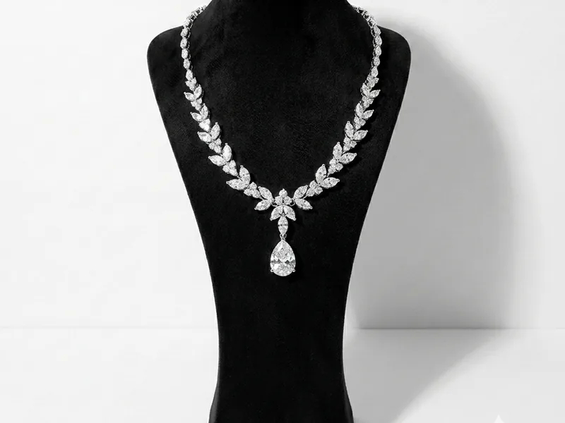 A crystal statement necklace displayed on a black velvet bust against a plain white backdrop, with a hard shadow to one side